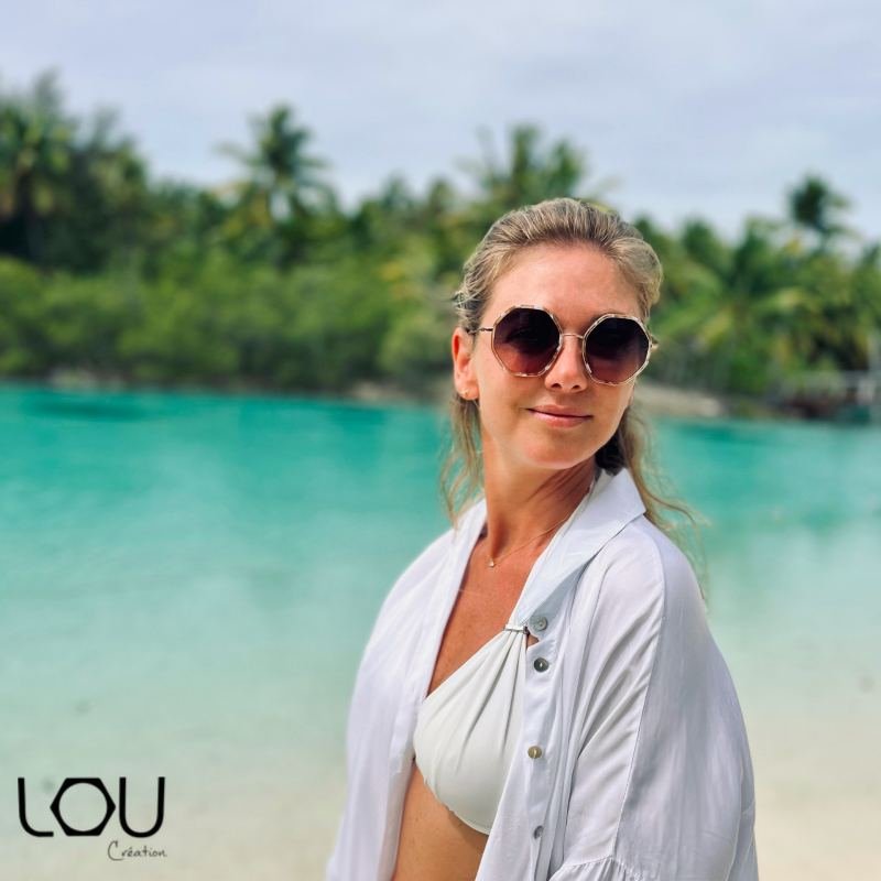 Femme portant des lunettes de soleil rondes à monture dorée au bord de l'eau
